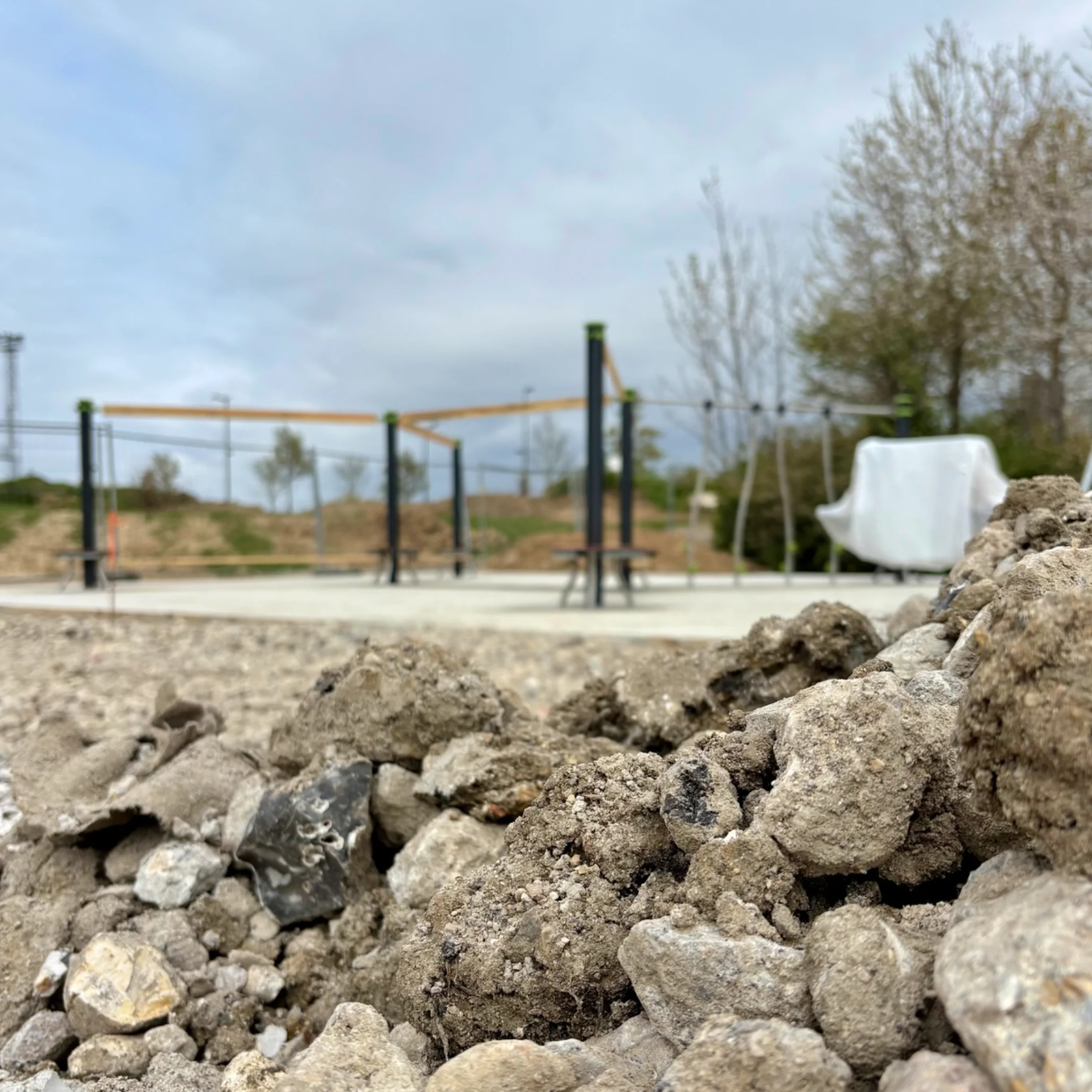 Chantier aire de jeux avec cailloux et jeux dans le fond