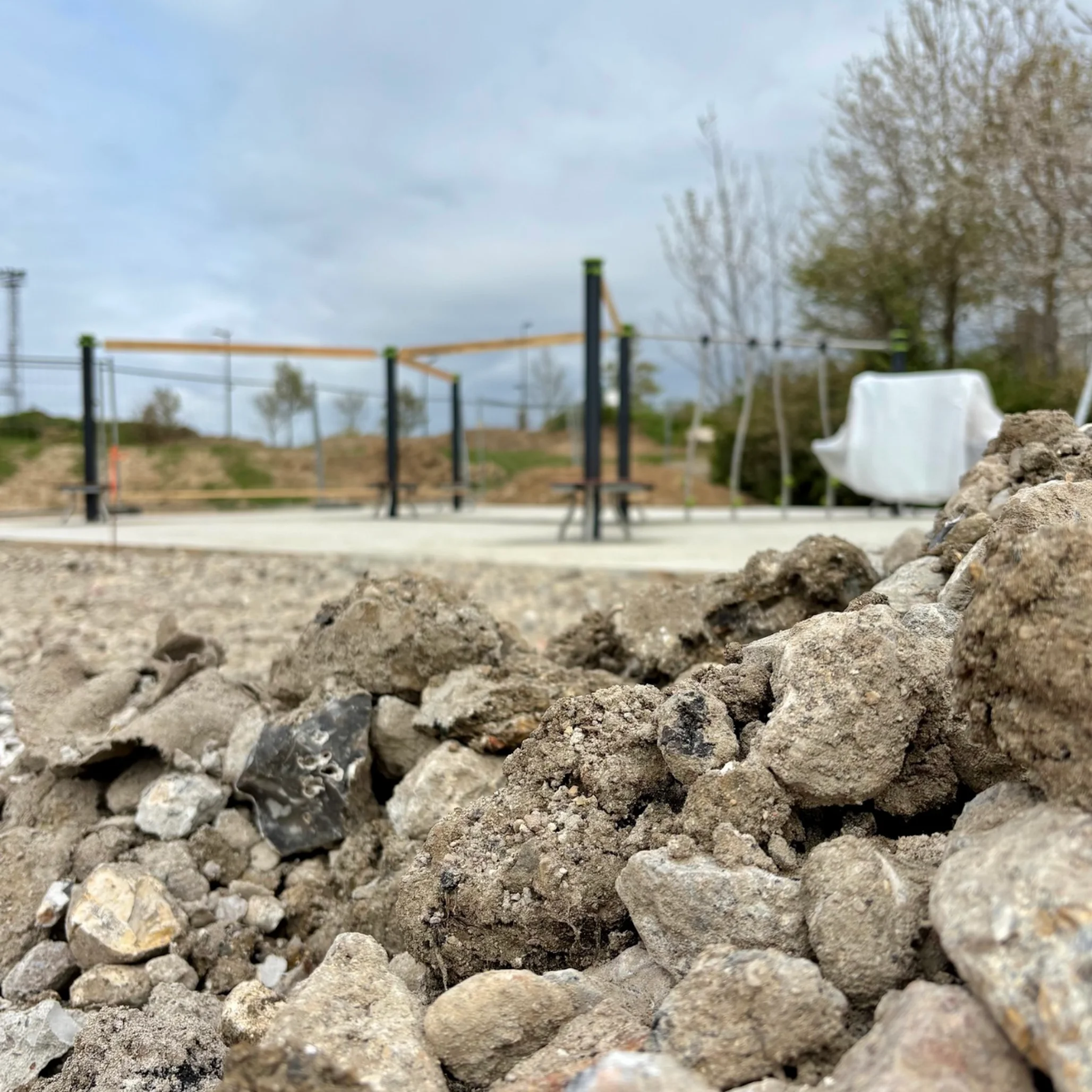 chantier aire de jeux quartier des meuniers avec des cailloux et en fond les jeux