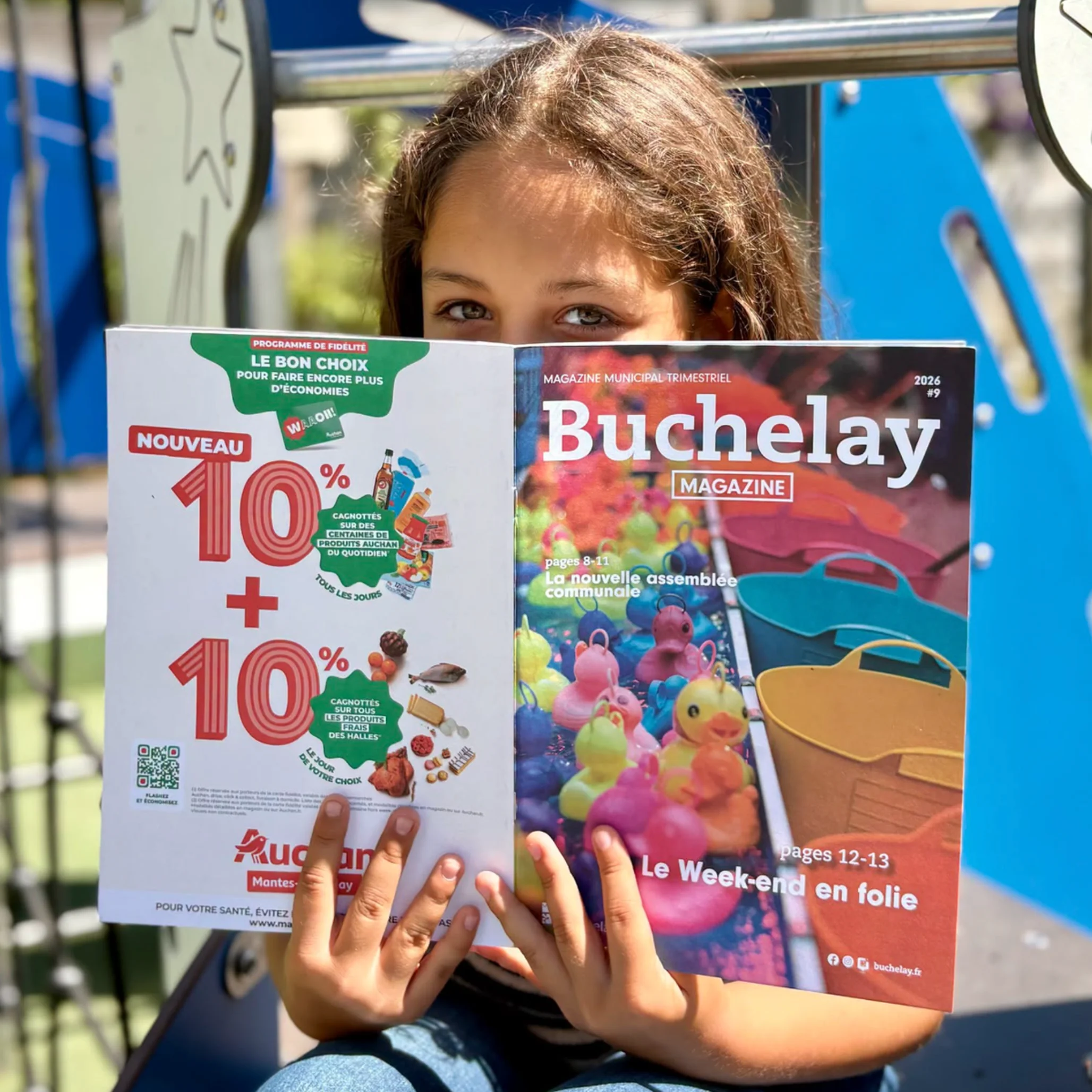 Petite fille avec le buchelay magazine du mois de juin devant le visage